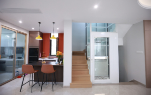 Contemporary elevator with wooden stairs in a modern home interior.