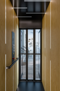 Contemporary elevator with glass doors and wooden paneling for smooth ride.
