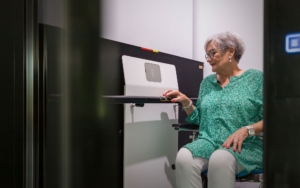 Elderly woman operating elevator control panel for home installation.
