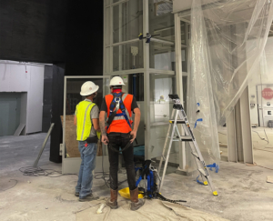 Two workers installing elevator components at a construction site.