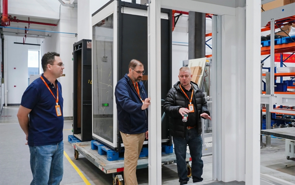 men evaluating elevator assembly at factory
