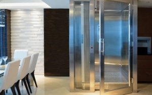 Stainless steel commercial elevator with glass doors in modern office lobby.
