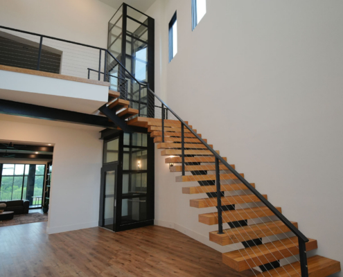 Residential elevator installed adjacent to a staircase